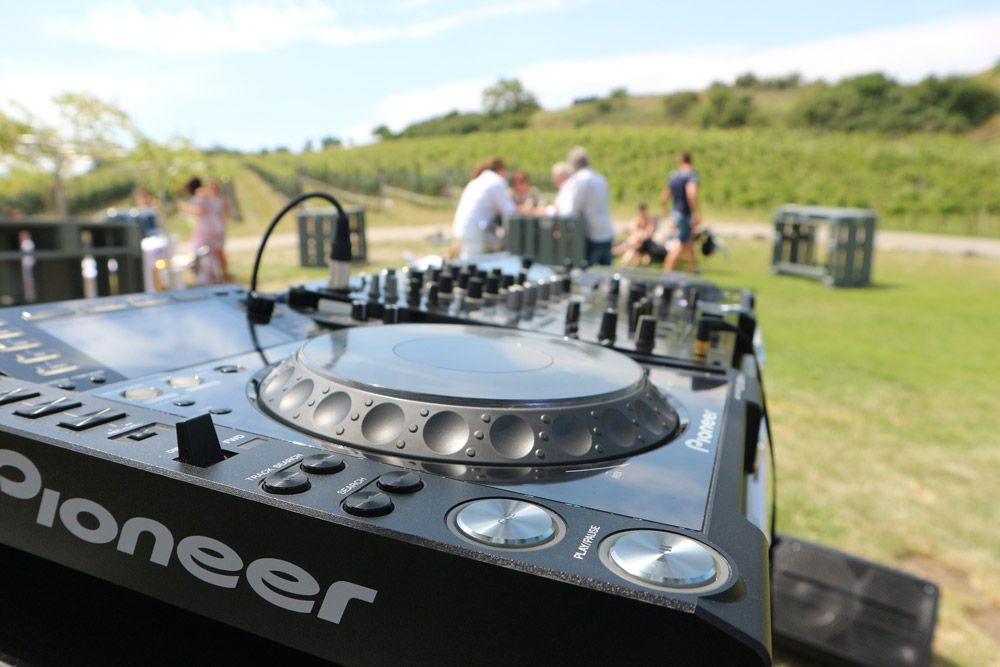 Pioneer CD Player und Mischpult im Vordergrund und im Hintergrund das Weingut Leo Hillinger